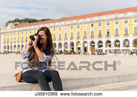 Stock Photo - Young female tourist photographing in Rossio Square, Lisbon, Portugal. Fotosearch