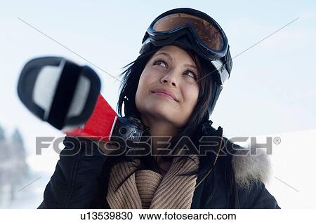 Young female wearing ski goggles and carrying skis View Large Photo Image Stock Image - Young female wearing ski goggles and carrying skis. Fotosearch