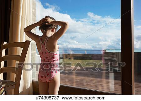 Young girl wearing bathing costume looking out of window View Large Photo Image Stock Photo - Young girl wearing bathing costume looking out of window. Fotosearch