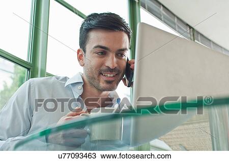 Young male office worker talking on mobile phone View Large Photo Image Stock Image - Young male office worker talking on mobile phone. Fotosearch