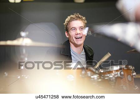 Stock Photo - Young male playing drum kit in music store. Fotosearch