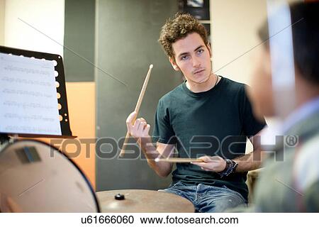 Stock Image - Young male teaching boy how to play drum kit. Fotosearch