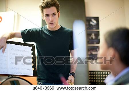 Stock Photo - Young male teaching boy how to play drums. Fotosearch