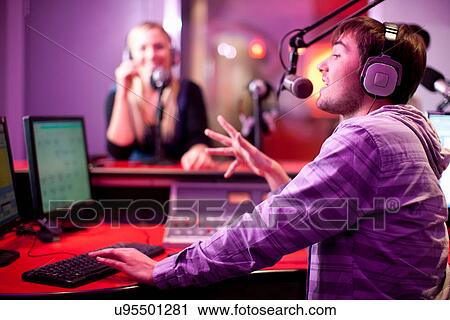 Stock Image - Young man and woman broadcasting in recording studio. Fotosearch