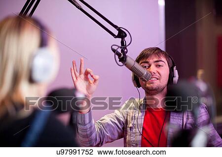Stock Image - Young man and woman broadcasting in recording studio. Fotosearch