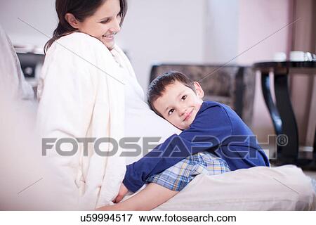 Stock Photo - Young son hugging mothers bump. Fotosearch