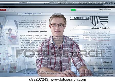 Stock Image - Young student looking at university prospectus on screen. Fotosearch