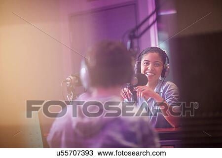 Stock Image - Young woman and man broadcasting in recording studio. Fotosearch