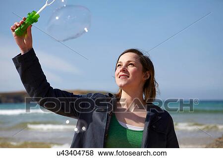 Young woman at coast with bubble wand View Large Photo Image Stock Photo - Young woman at coast with bubble wand. Fotosearch