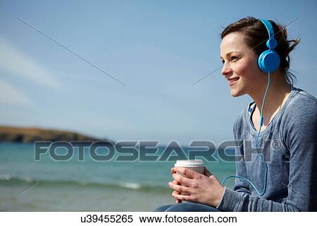 Young woman at coast with coffee and earphones View Large Photo Image Stock Photography - Young woman at coast with coffee and earphones. Fotosearch