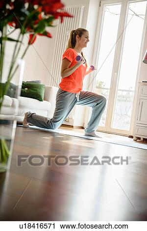 Young woman exercising with dumb-bells at home View Large Photo Image Stock Image - Young woman exercising with dumb-bells at home. Fotosearch