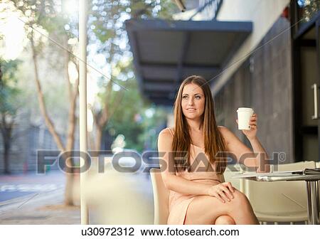 Young woman holding coffee in street cafe View Large Photo Image Stock Image - Young woman holding coffee in street cafe. Fotosearch
