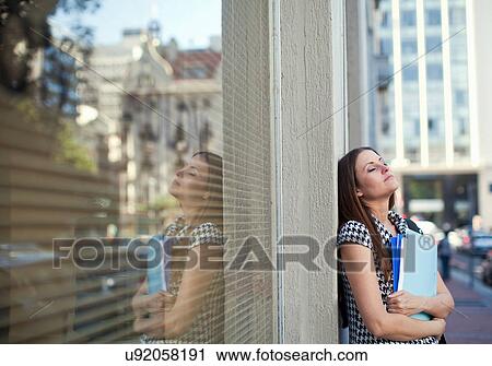 Stock Image - Young woman holding files outside city office. Fotosearch