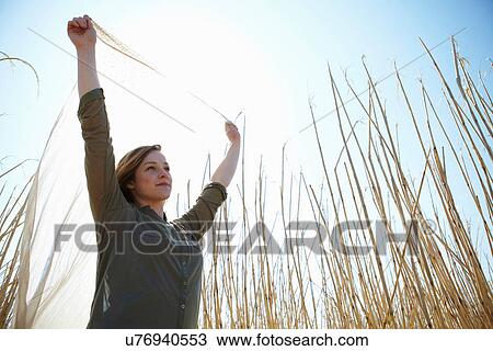 Young woman holding up scarf in reeds View Large Photo Image Stock Image - Young woman holding up scarf in reeds. Fotosearch