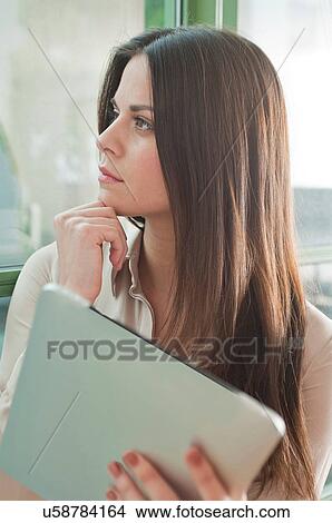 Young woman in office looking out of window View Large Photo Image Picture - Young woman in office looking out of window. Fotosearch