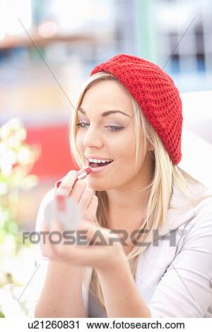 Young woman in red knitted hat applying lipstick View Large Photo Image Stock Image - Young woman in red knitted hat applying lipstick. Fotosearch