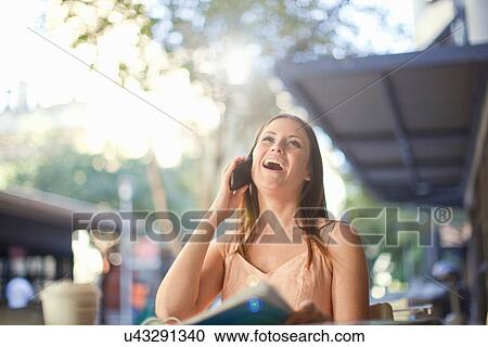 Young woman laughing whilst on mobile in street cafe View Large Photo Image Stock Image - Young woman laughing whilst on mobile in street cafe. Fotosearch