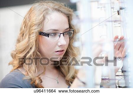 Young woman looking at eyeglasses display View Large Photo Image Picture - Young woman looking at eyeglasses display. Fotosearch