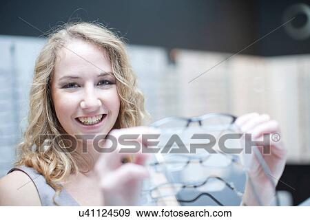 Young woman looking at eyeglasses View Large Photo Image Stock Photo - Young woman looking at eyeglasses. Fotosearch