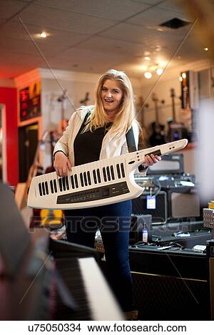 Young woman playing keytar in music store View Large Photo Image Picture - Young woman playing keytar in music store. Fotosearch