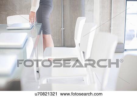 Stock Image - Young woman preparing boardroom table. Fotosearch