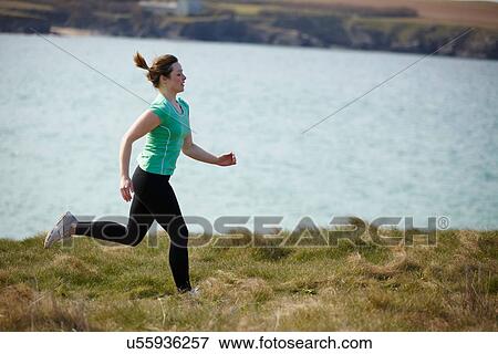 Young woman running near coast View Large Photo Image Stock Photo - Young woman running near coast. Fotosearch