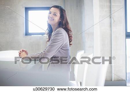 Young woman sitting at boardroom table View Large Photo Image Stock Image - Young woman sitting at boardroom table. Fotosearch