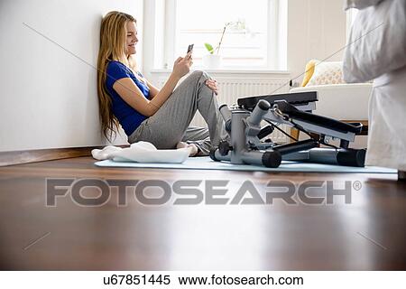 Young woman sitting on bedroom floor looking at smartphone View Large Photo Image Stock Photography - Young woman sitting on bedroom floor looking at smartphone. Fotosearch