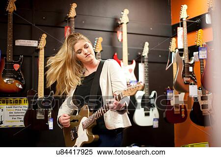 Young woman testing guitar in music store View Large Photo Image Stock Photography - Young woman testing guitar in music store. Fotosearch