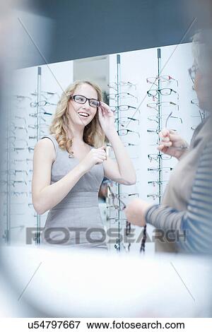 Young woman trying on eyeglasses in shop View Large Photo Image Stock Photo - Young woman trying on eyeglasses in shop. Fotosearch