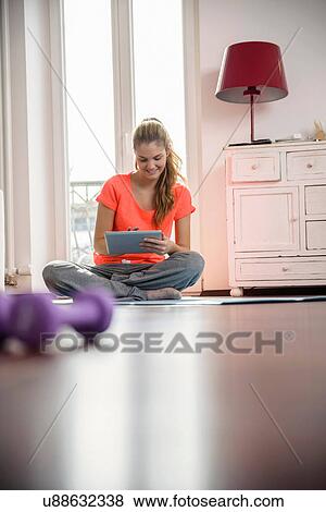 Young woman using digital tablet at home View Large Photo Image Stock Photo - Young woman using digital tablet at home. Fotosearch