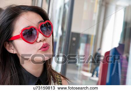 Stock Image - Young woman wearing heart sunglasses, shopping in London, UK. Fotosearch