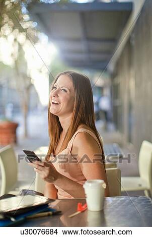 Picture - Young woman with mobile in street cafe. Fotosearch