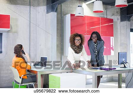 Stock Image - Young women in creative office. Fotosearch