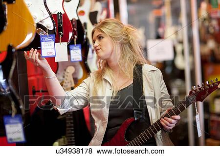 Stock Photo - Young women looking at guitars in music store. Fotosearch