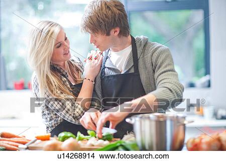 Affectionate young couple preparing food View Large Photo Image Picture - Affectionate young couple preparing food. Fotosearch