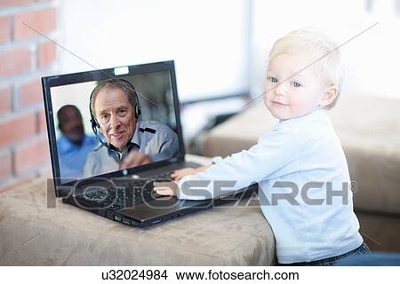 Picture - Baby boy distracted on video call. Fotosearch