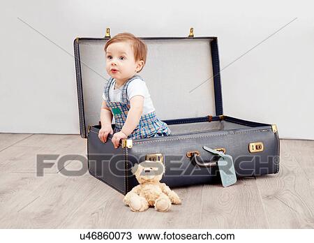 Stock Image - Baby boy sitting in suitcase. Fotosearch