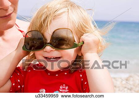 Stock Photo - Baby girl wearing sunglasses upside down. Fotosearch
