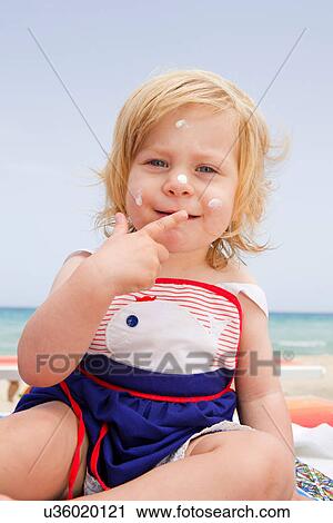 Stock Image - Baby girl with suncream on face. Fotosearch