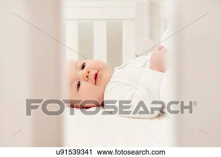 Stock Image - Baby in crib by herself. Fotosearch