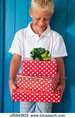 Stock Image - Boy looking down at gifts. Fotosearch