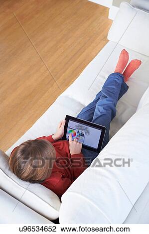 Stock Image - Boy on sofa using digital tablet. Fotosearch