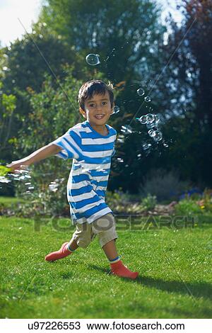 Boy playing with bubbles in garden View Large Photo Image Stock Image - Boy playing with bubbles in garden. Fotosearch