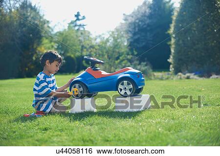 Boy pretending to fix toy car View Large Photo Image Stock Photograph - Boy pretending to fix toy car. Fotosearch
