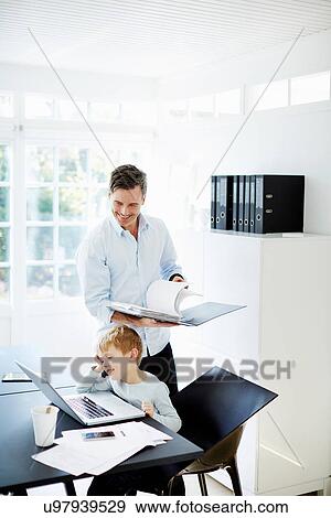 Boy using laptop and man looking at paperwork View Large Photo Image Stock Photo - Boy using laptop and man looking at paperwork. Fotosearch