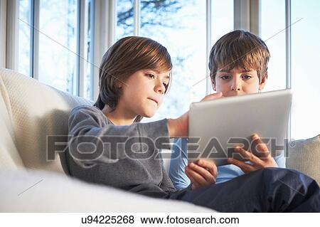 Stock Photo - Brothers using digital tablet together. Fotosearch