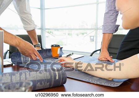 Stock Image - Business executives discussing chart at meeting. Fotosearch