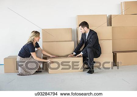 Businessman and -woman lifting cardboard box View Large Photo Image Picture - Businessman and -woman lifting cardboard box. Fotosearch