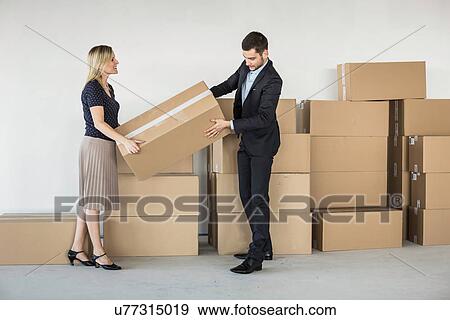 Businessman and -woman lifting cardboard box View Large Photo Image Stock Photo - Businessman and -woman lifting cardboard box. Fotosearch